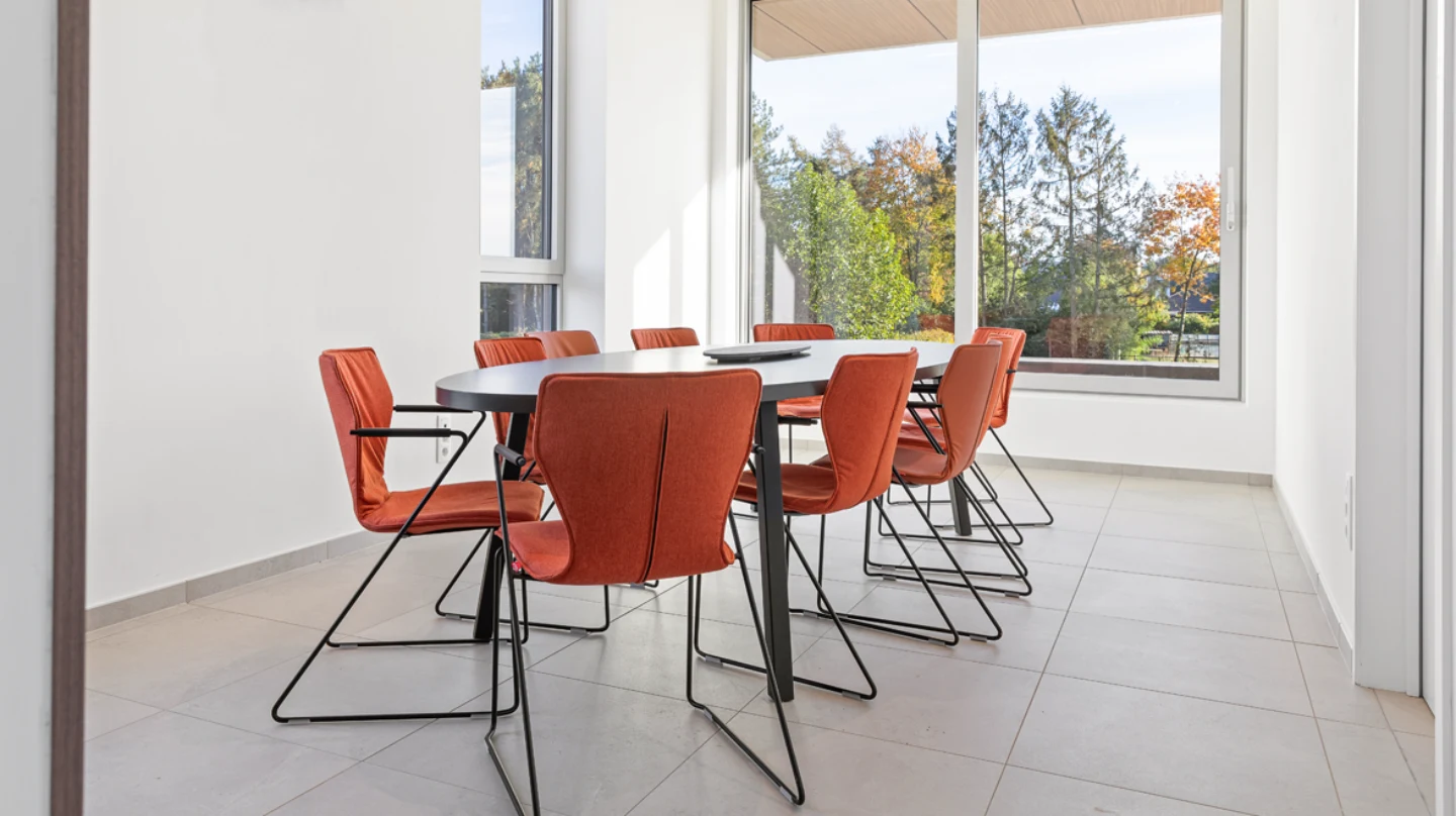 vergaderzaal met oranje vergaderstoelen en ovale tafel