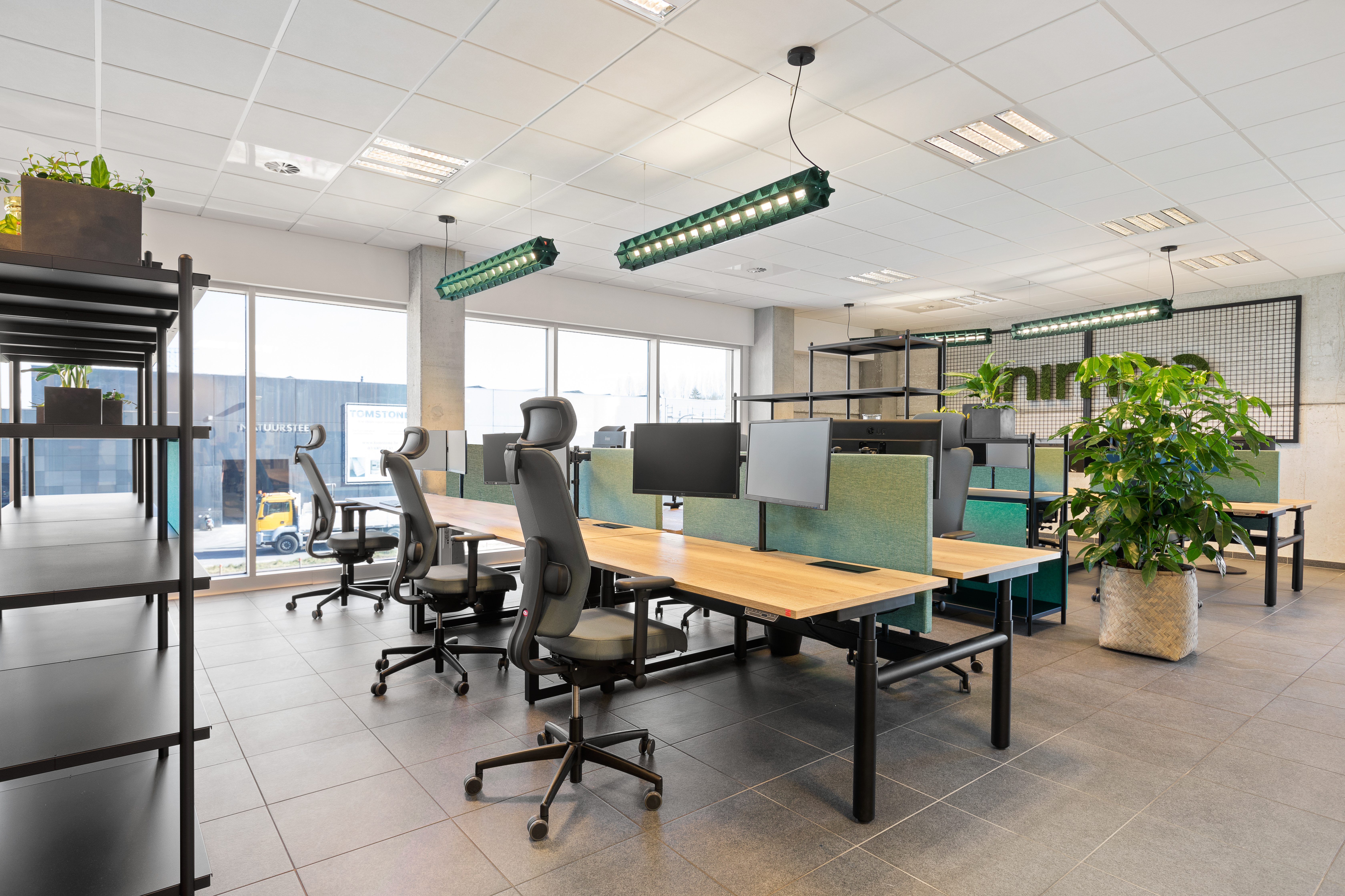 Kantoorruimte met Prio zit-sta bureaus en EXP lampen uit groen vilt