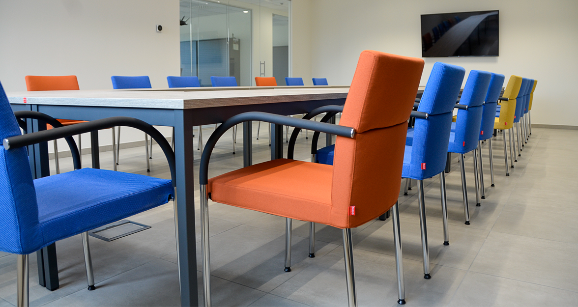 vergaderzaal met oranje en blauwe vergaderstoelen in huisstijl kleuren